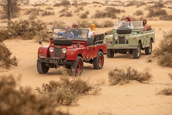 Experience the serene beauty of the desert as you journey in vintage Land Rovers surrounded by stunning landscapes and the promise of adventure ahead. Perfect for unforgettable memories.